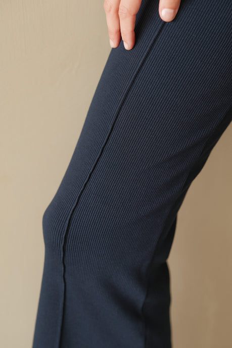 A close up of a woman's leg wearing the navy rib kick flare pant.