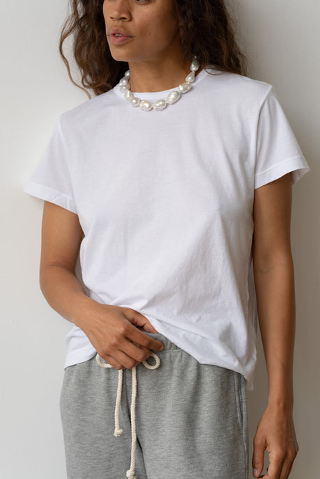 A woman wearing The Jersey Tee in white, the June White Pearl Choker, with the Eco-Terry Sweatpants.