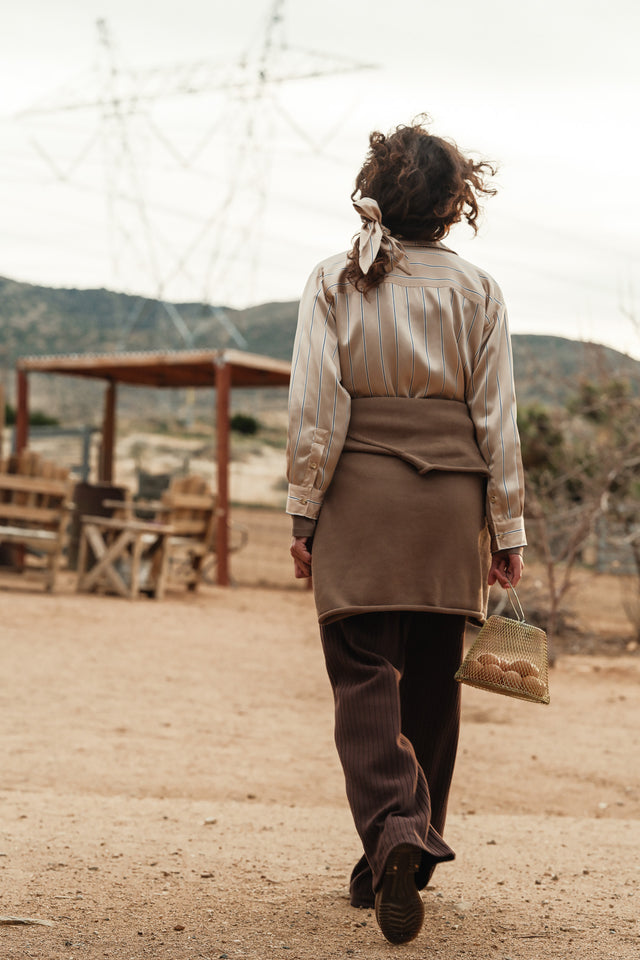 Woman wearing a striped silk bow at a farm holding a basket of eggs.